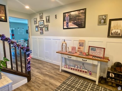 Recreation room with a decorative wall, wood finished floors, a wainscoted wall, and recessed lighting