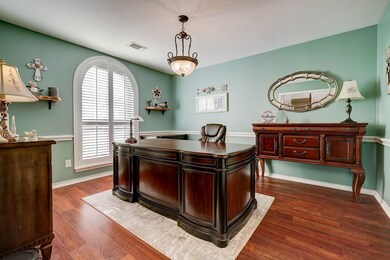 A lovely home office is located near the foyer, which would also make an ideal formal dining room. Features include a custom chandelier, chair rail, accent paint, and a large rounded window with plantation shutters overlooking the front yard.