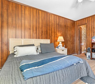 Bedroom with wooden walls, a ceiling fan, and wood