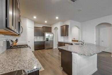 Kitchen featuring tasteful backsplash, appliances with stainless steel finishes, and dark wood-type flooring