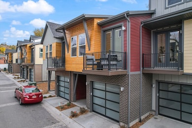 View of home's exterior with a residential view, a balcony, an attached garage, concrete driveway, and brick siding