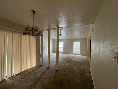 Carpeted empty room featuring an inviting chandeli