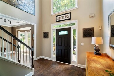 Foyer entrance featuring real wood finished floors, healthy amount of natural light, stairway, ornamental molding, and a towering ceiling