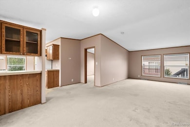 Unfurnished living room with healthy amount of natural light, ornamental molding, and light colored carpet