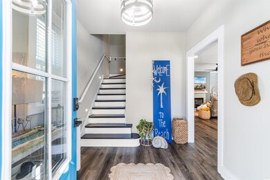 Foyer entrance with ceiling fan and dark wood-type