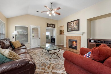 Main living area with gas log fireplace, high ceilings, upgraded wood/laminate flooring, large TV nook, easy access to the covered patio in the back and the 