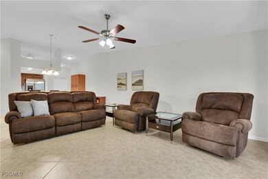Living area featuring lofted ceiling, light tile patterned floors, a chandelier, and ceiling fan