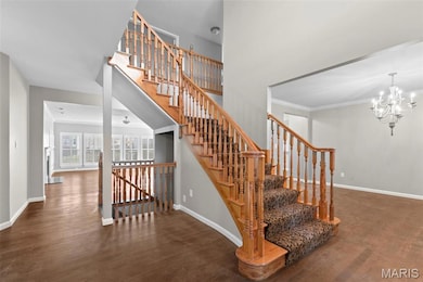 Stairway featuring wood finished floors, a chandelier, and ornamental molding