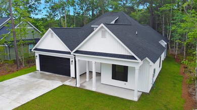 View of front of property featuring a shingled roof, a front yard, concrete driveway, covered porch, and a garage