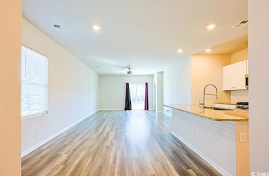 Kitchen featuring light stone countertops, white cabinetry, light wood-style flooring, open floor plan, and recessed lighting
