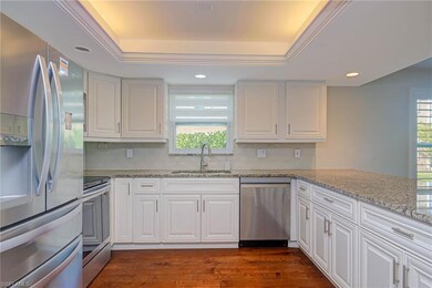 Kitchen with sink, stainless steel appliances, a healthy amount of sunlight, white cabinets, and a raised ceiling