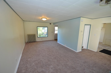 Carpeted spare room featuring radiator heating uni