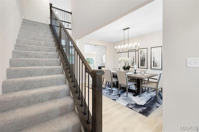Dining area with light wood-type flooring, stairs, and a chandelier