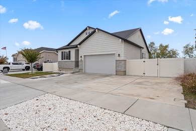 View of front facade with a gate, driveway, stone siding, garage, RV parking