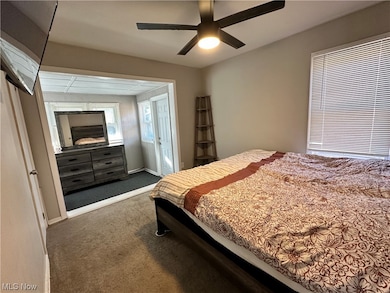 Carpeted bedroom with ceiling fan and a fireplace