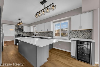 Kitchen featuring decorative backsplash, beverage cooler, decorative light fixtures, and stainless steel range with electric stovetop