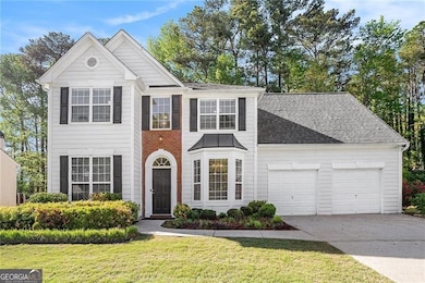 View of front of home featuring a front yard, an attached garage, a shingled roof, and driveway