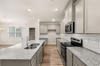 Kitchen featuring gray cabinetry, appliances with stainless steel finishes, light wood-type flooring, ornamental molding, and tasteful backsplash