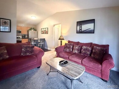 Living area featuring lofted ceiling, visible vents, baseboards, and carpet floors