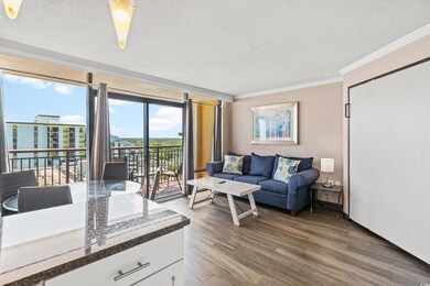 Living room featuring a textured ceiling, wood-type flooring, ornamental molding, and a wall of windows