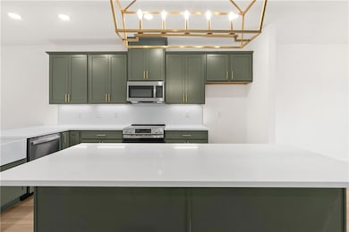 Kitchen featuring green cabinetry, appliances with stainless steel finishes, light countertops, and recessed lighting