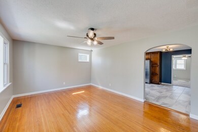 Spacious Living Room with views to Front Yard!  Arched Doorways leading to Eat In Kitchen & one leads to 2 of the 3 Bedrooms. Beautifully renewed hardwood floors, Ceiling Fan & Freshly Painted. 