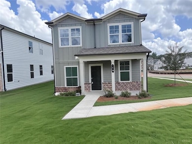 View of front of home featuring board and batten siding, a front yard, brick siding, and covered porch
