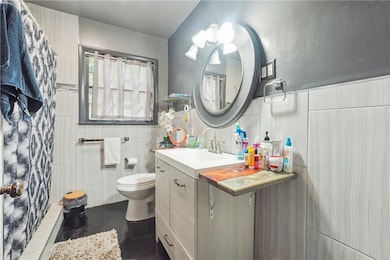 Bathroom featuring vanity, a shower stall, and tile walls