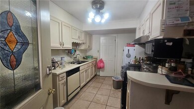 Kitchen featuring white appliances, a sink, under cabinet range hood, light countertops, and light tile patterned floors