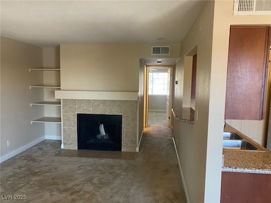 Unfurnished living room featuring dark carpet and a tiled fireplace