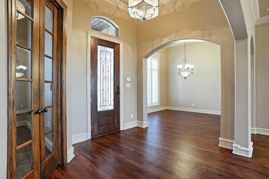 Foyer featuring an inviting chandelier, arched walkways, custom baseboards and oakwood finished floor