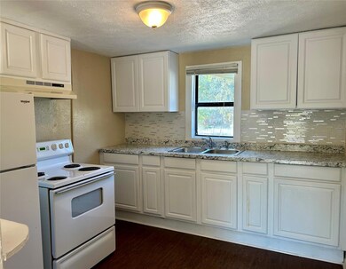 Kitchen with exhaust hood, white cabinets, sink, and white appliances