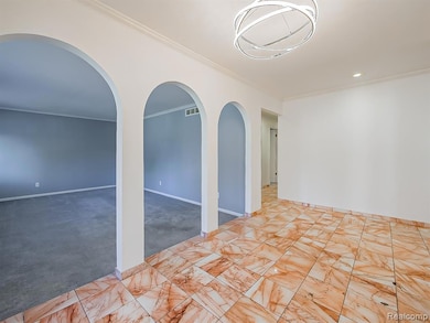 Empty room with carpet floors, crown molding, recessed lighting, and arched walkways