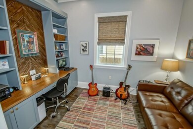 Office w/ custom desk and shelves just past foyer