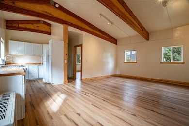 Unfurnished living room with beamed ceiling, light wood-style floors, and high vaulted ceiling