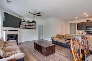 Living area featuring ceiling fan, wood finished floors, a glass covered fireplace, and recessed lighting