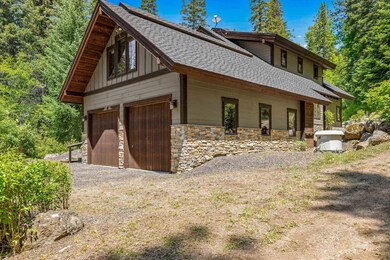 View of side of property featuring architectural roof shingles, stone siding