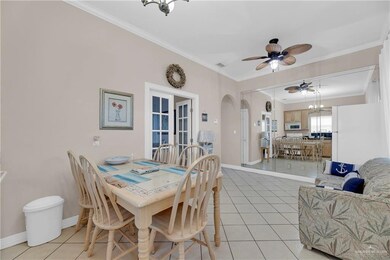 Tiled dining area with ceiling fan with notable chandelier and ornamental molding