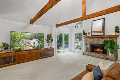 plenty of natural light through windows and doors all anchored by a stone, gas log fireplace adding warmth and charm