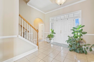 Foyer entrance with ornamental molding, stairway, arched walkways, light tile patterned floors, and baseboards