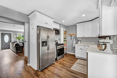 Kitchen with white cabinets, stainless steel appliances, light hardwood / wood-style floors