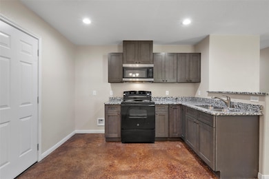 Kitchen featuring black / electric stove, finished concrete floors, light stone countertops, stainless steel microwave, and recessed lighting