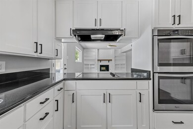 Kitchen featuring white cabinets, ventilation hood