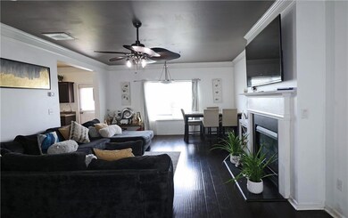 Living area with ceiling fan, a high end fireplace, dark wood-style floors, and crown molding