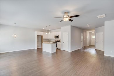 Unfurnished living room with a sink, ceiling fan, baseboards, a chandelier, and recessed lighting