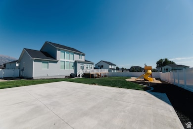 Rear view of house featuring a fenced backyard, a deck, and a playground