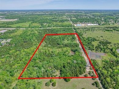 Aerial view of property and surrounding area featuring property boundaries highlighted and a heavily wooded area