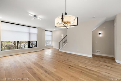 Unfurnished living room featuring light wood finished floors, stairway, and recessed lighting