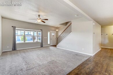 Unfurnished living room featuring ceiling fan, dar