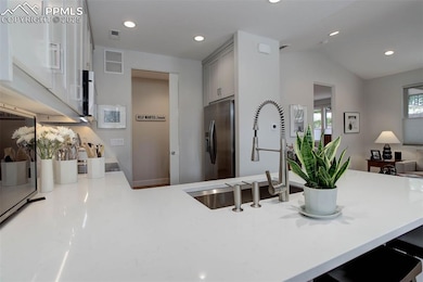 Kitchen with stainless steel fridge with ice dispenser, a sink, lofted ceiling, light countertops, and recessed lighting
